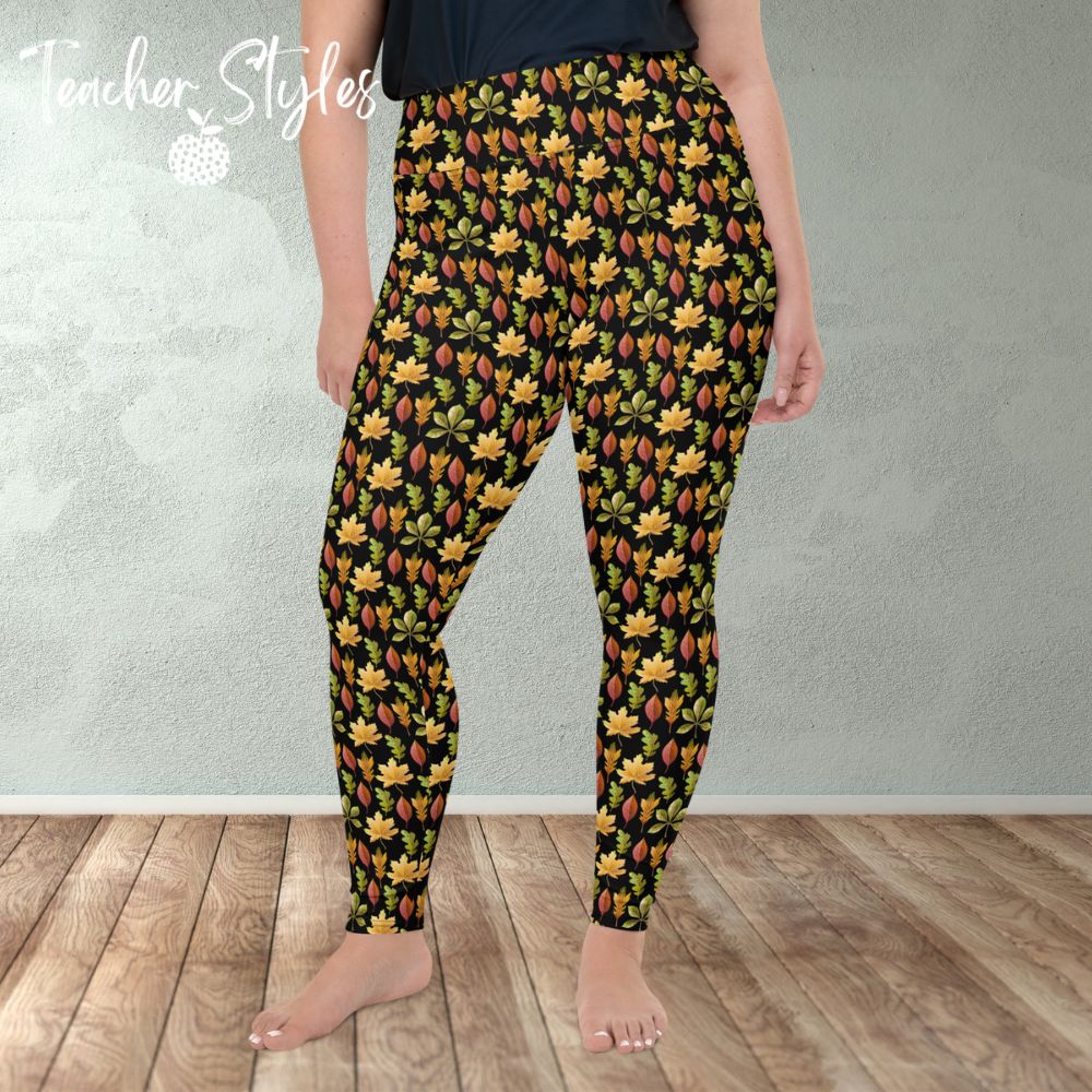 Autumn Leaves plus size leggings - black by Teacher Styles. Model is shown from the waist down. Leggings have black background and pattern of yellow maple, green oak and red elm leaves. front view