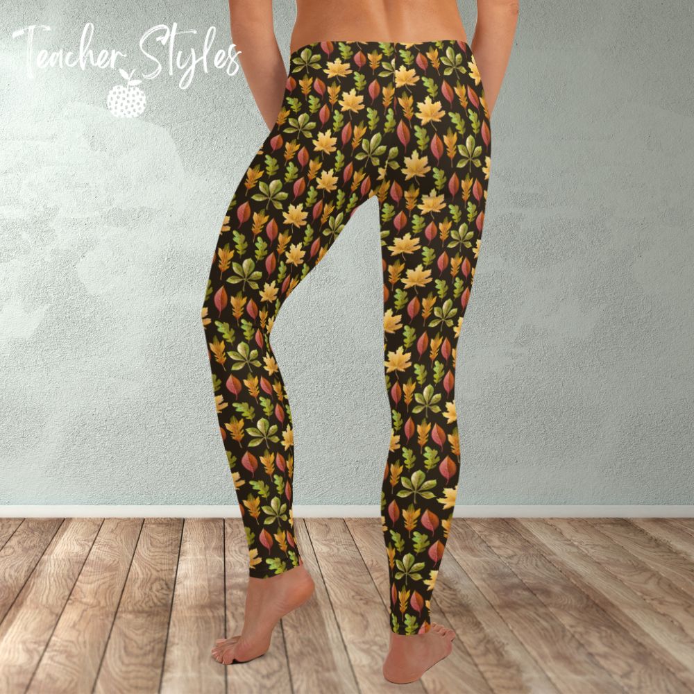 Autumn Leaves leggings - brown by Teacher Styles. Model is shown from the waist down. Leggings have brown background and pattern of yellow maple, green oak and red elm leaves. back view