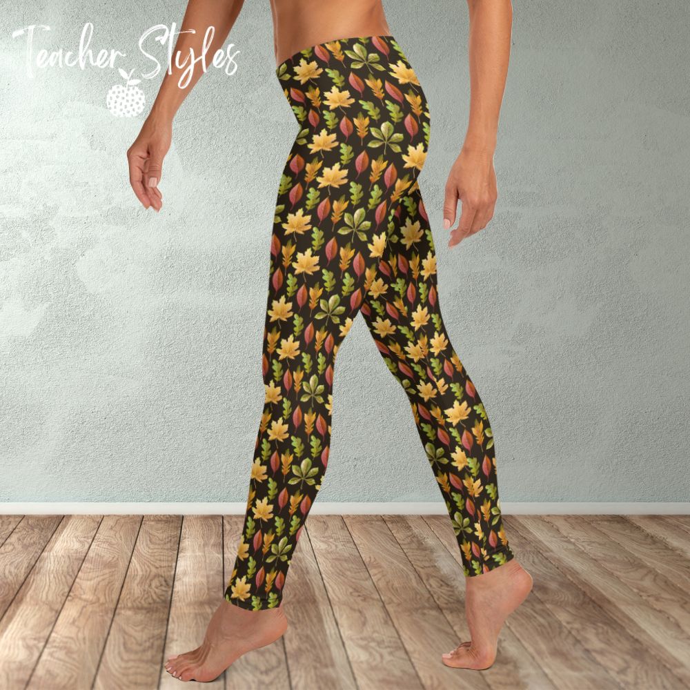 Autumn Leaves leggings - brown by Teacher Styles. Model is shown from the waist down. Leggings have brown background and pattern of yellow maple, green oak and red elm leaves. side view