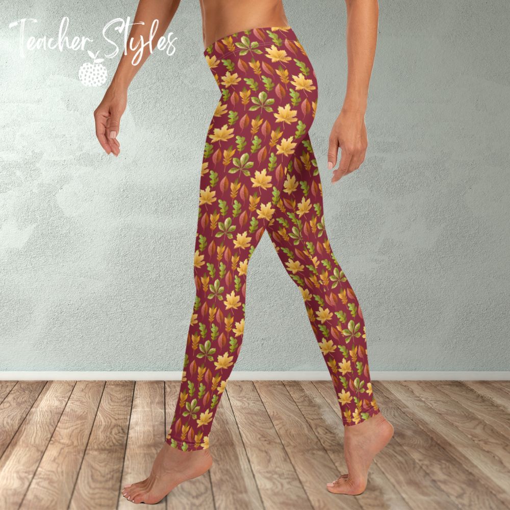 Autumn Leaves leggings - burgundy by Teacher Styles. Model is shown from the waist down. Leggings have burgundy background and pattern of yellow maple, green oak and red elm leaves. side view