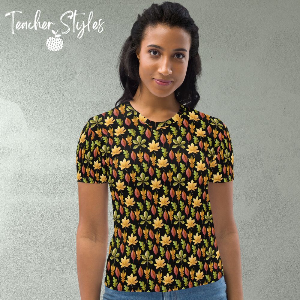 Autumn Leaves t-shirt - black by Teacher Styles. Model is shown from the waist up .T-shirt has a black background and pattern of yellow maple, green oak and red elm leaves. front view