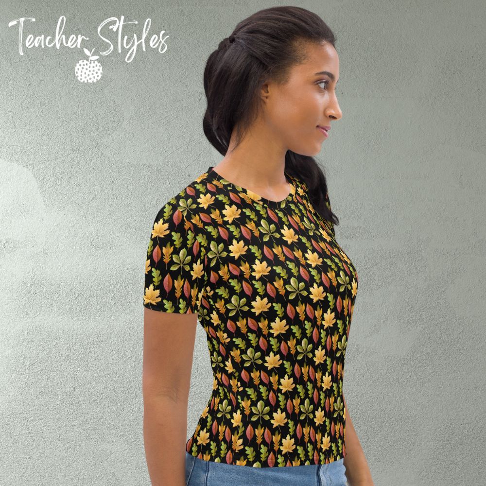 Autumn Leaves t-shirt - black by Teacher Styles. Model is shown from the waist up .T-shirt has a black background and pattern of yellow maple, green oak and red elm leaves. side view