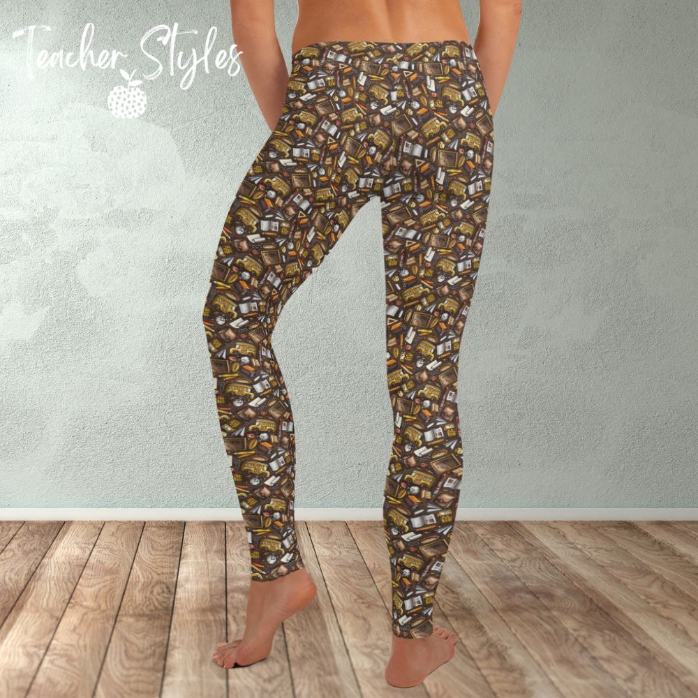 Back to Basics leggings by Teacher Styles. Model is shown from the waist down. Leggings have brown background and pattern of yellow school buses, chalkboards, clocks and more! back view