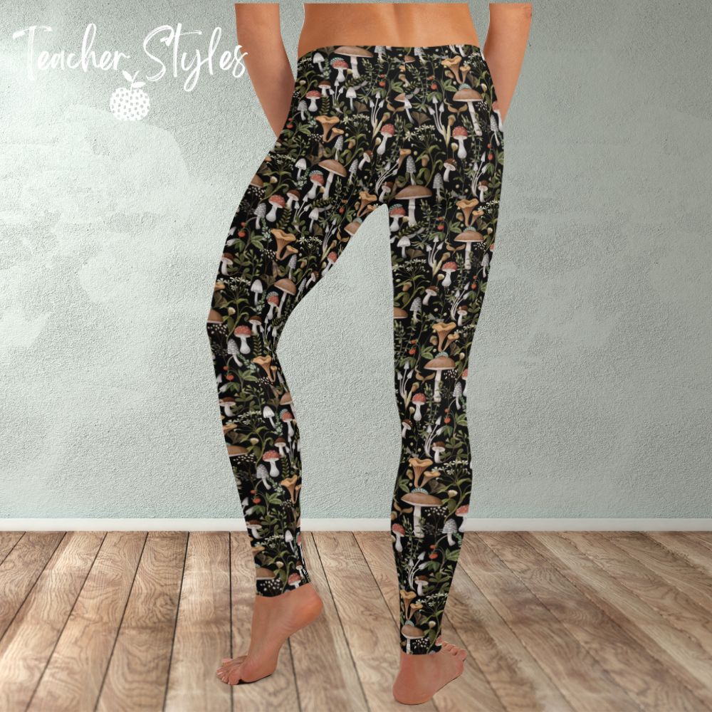 Fungi Fun leggings - black by Teacher Styles. Model is shown from the waist down. Leggings have black background and pattern of forest mushrooms. back view