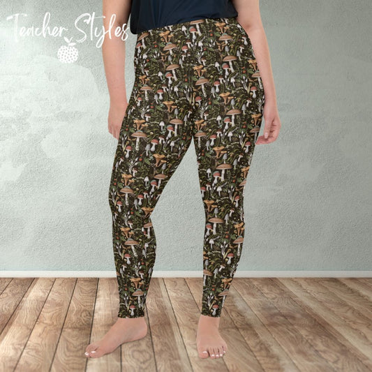 Fungi Fun plus size leggings - brown by Teacher Styles. Model is shown from the waist down. Leggings have black background and pattern of forest mushrooms.  front view