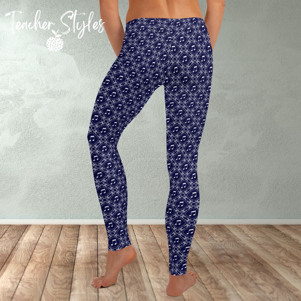 Musical Interlude leggings by Teacher Syles. Model is shown from the waist down.  Leggings have deep blue background with white lattice pattern made of treble clefs. Musical notes in each treble square. back  view