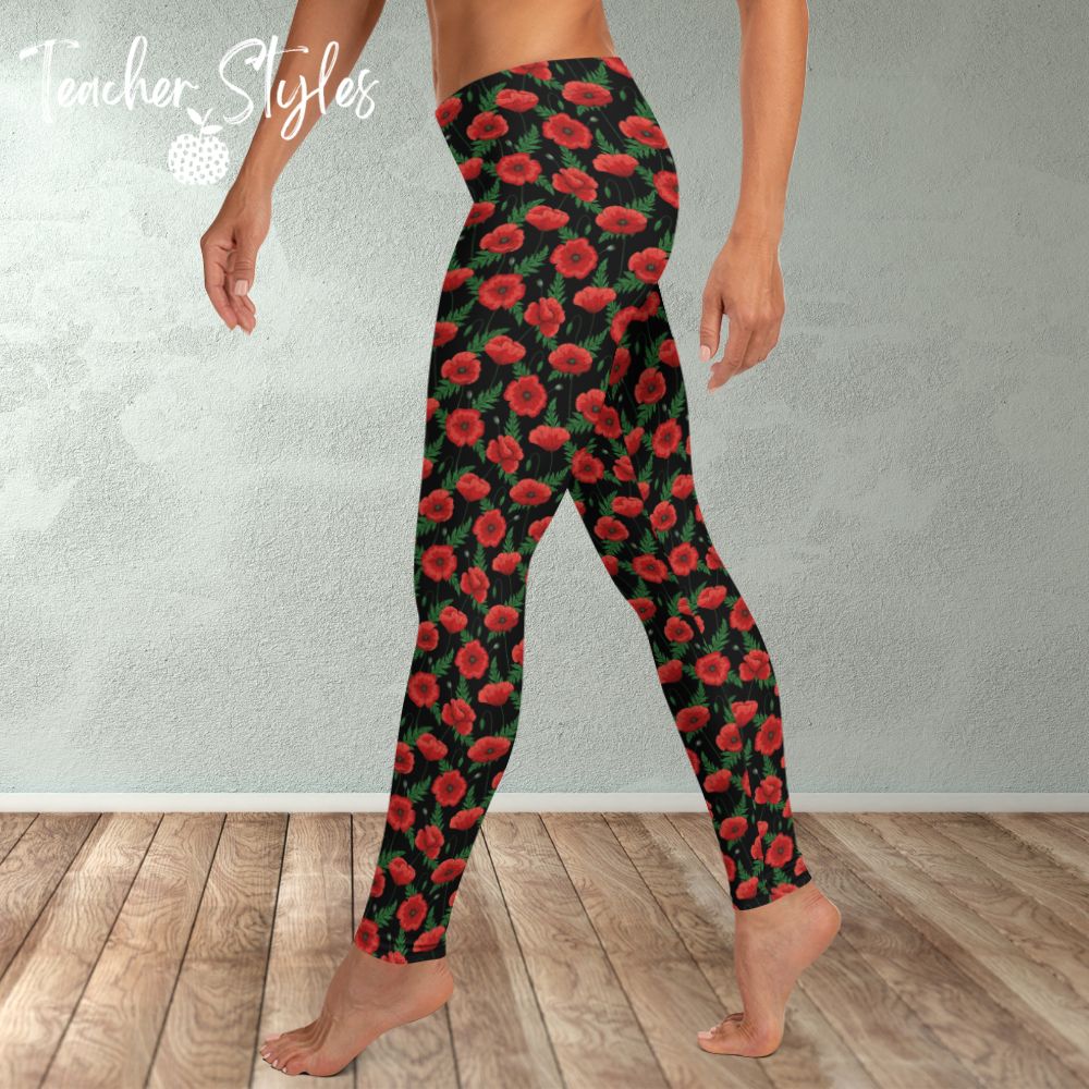 Poppies - black leggings by Teacher Styles. Model shown from the waist down. Leggings have black background with vibrant red poppies and greenery.  Side view. Also suitable for National Poppy Day, Armistice Day, Remembrance Day.
