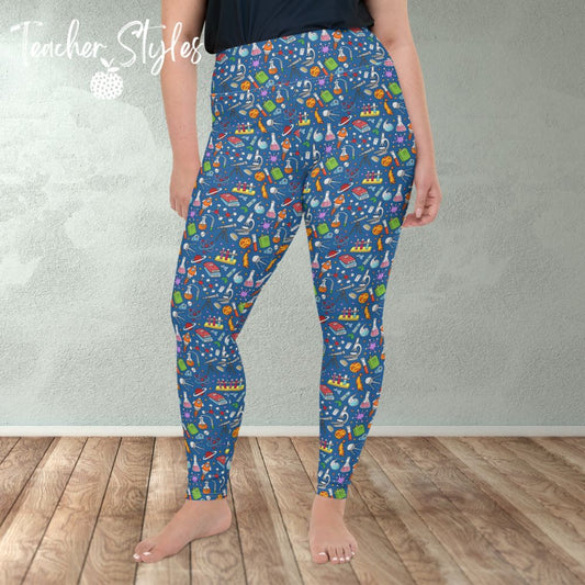 Science Leggings by Teacher Styles. Model image from the waist down shows light blue leggings overed in colorful science graphics - atoms, planets, beakers etc. Plus size. Front view. Model standing in room.