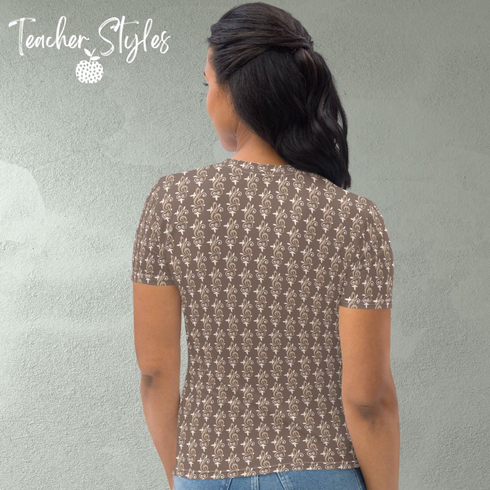 Simply Treble t-shirt by Teacher Syles. Model is shown from the waist up.  T-shirt has deep beige background with pattern of treble clefs. back view