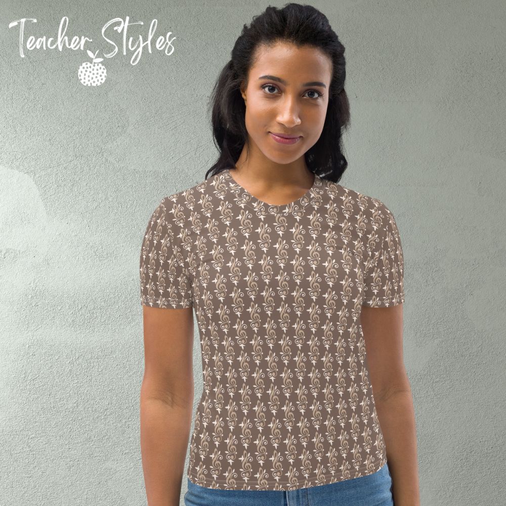 Simply Treble t-shirt by Teacher Syles. Model is shown from the waist up.  T-shirt has deep beige background with pattern of treble clefs. front view