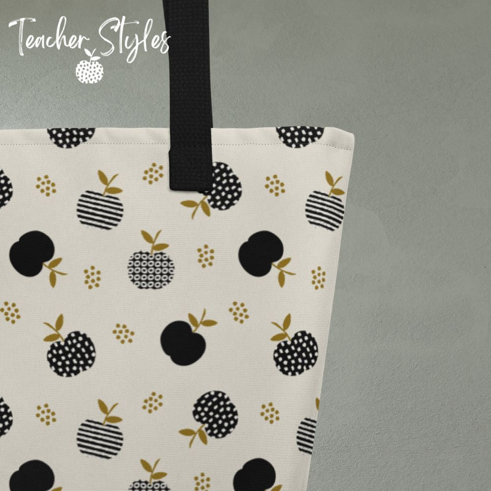 Close-up detail of tote showing Modern Apple print. Off white background with black apples in solids, stripes and dots. Goldish-brown leaf accents.