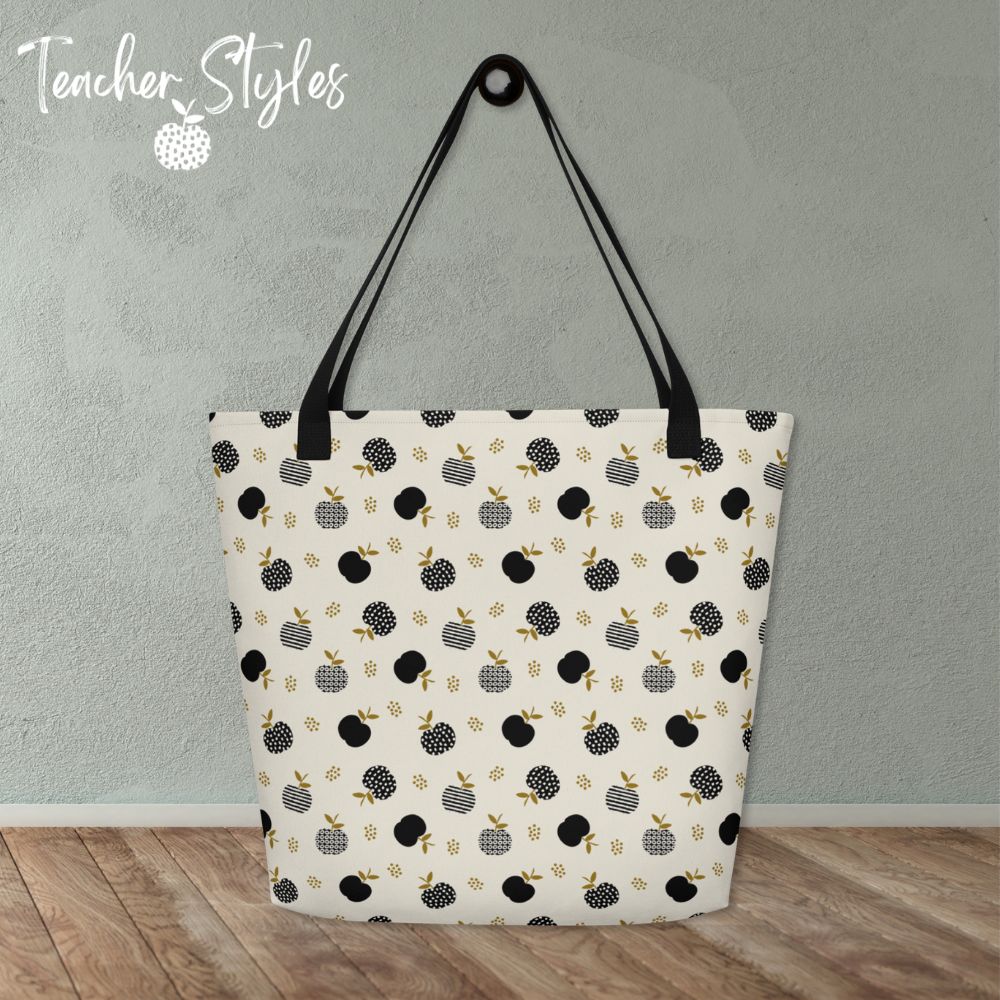 Modern Apple Tote by Teacher Styles. Tote print is off white with black apples in solids, stripes and dots. Black canvas web handles. Tote is sitting on table.