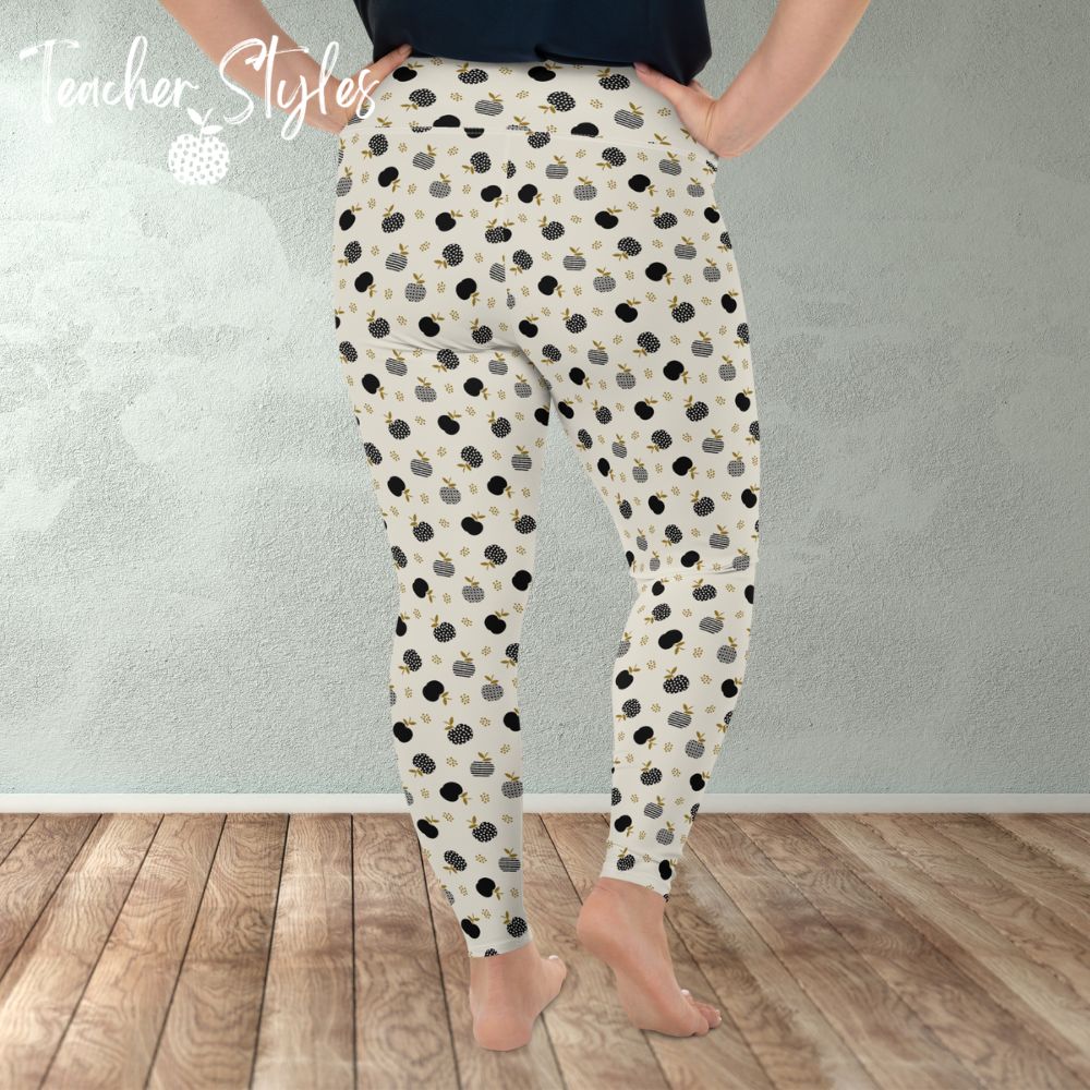 Modern Apple Plus Size Leggings by Teacher Styles. Image of woman from the waist down in room wearing leggings. Back view. Comfortable and stylish light beige/cream leggings featuring a pattern of black apples in solids, stripes and dots.  