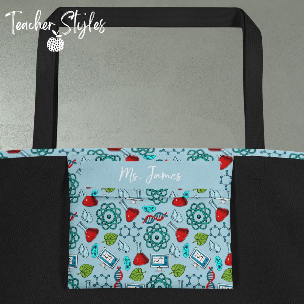 Science Tote Bag by Teacher Styles. Innerpocket detail shows name personalization available. Pocket in science print, rest of lining is black. Large light blue tote with pattern of science graphics - atoms, beakers, DNA and more! Black canvas webbed handles. 